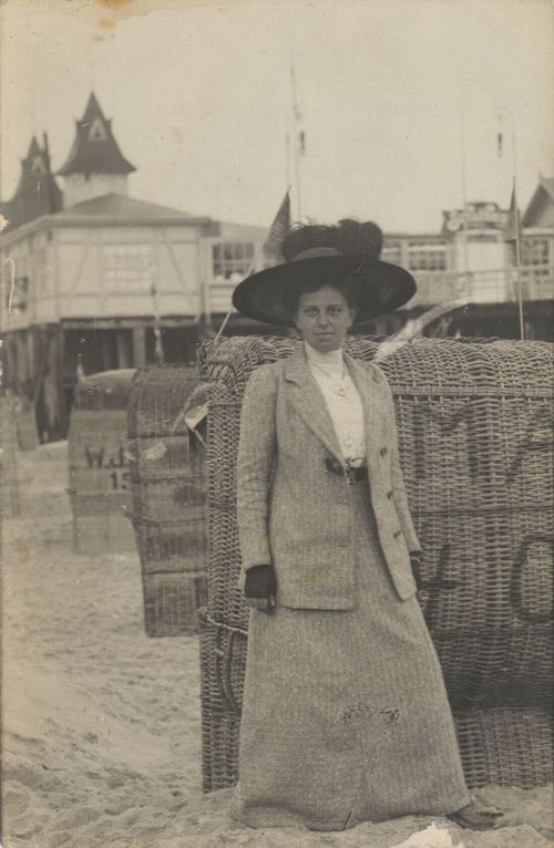 Dame mit Hut vor Seebrücke und Körben